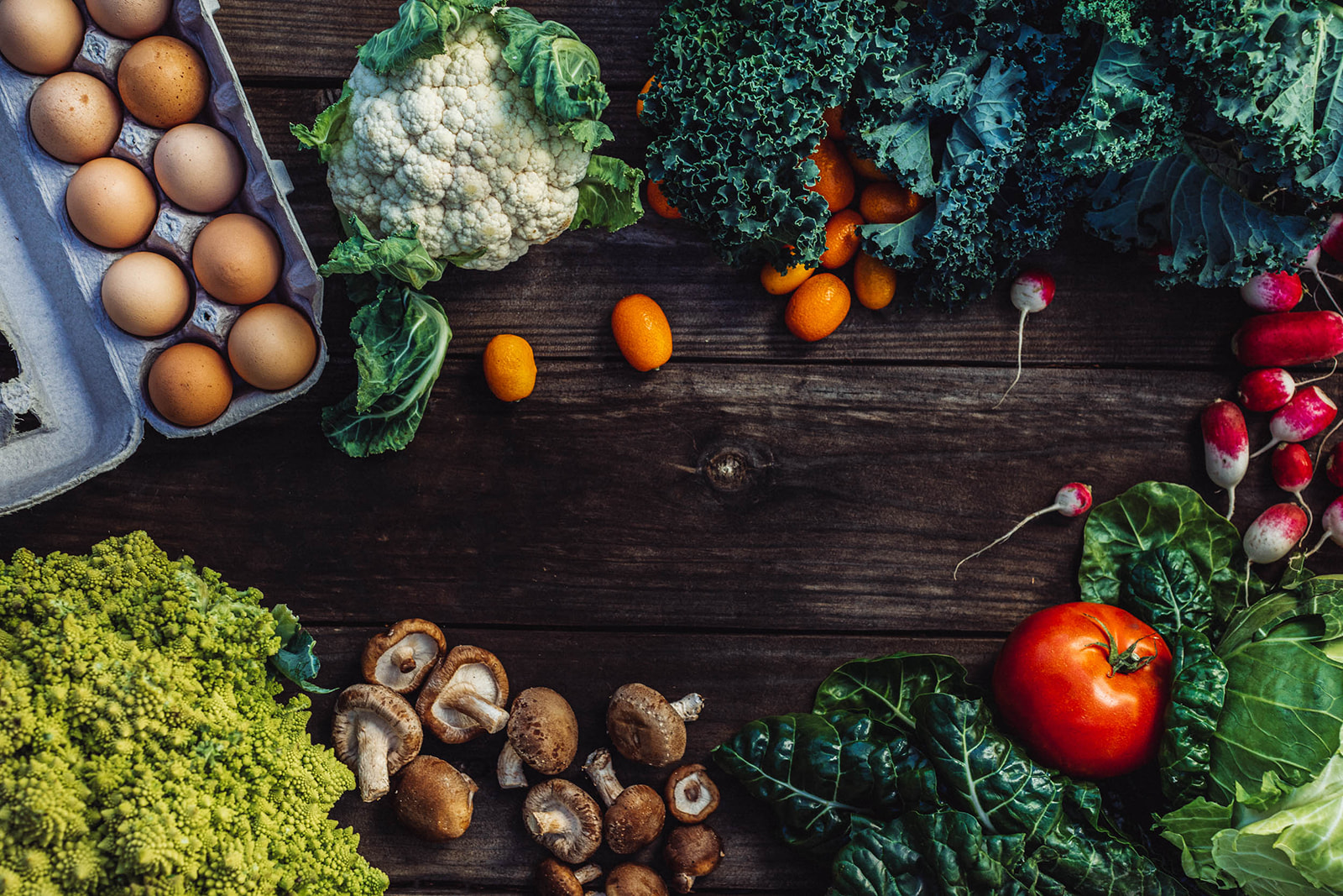 eggs, cauliflower, mushrooms, and assorted greens on a wooden table